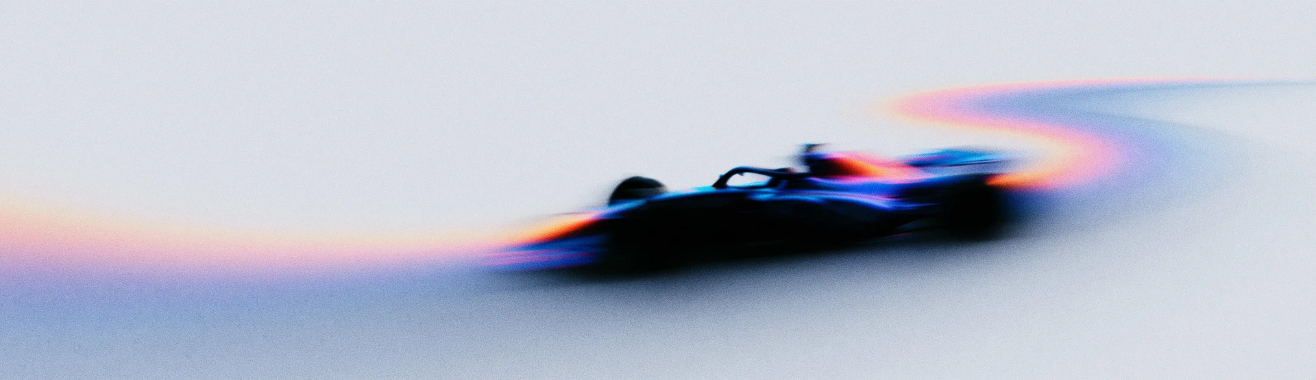 An open-wheel racing car in motion, with blue and orange light trailing across a pale background