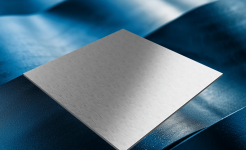 A smooth, reflective metal sheet displayed on a textured blue surface under soft lighting.